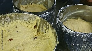 closeup view of three metal baking forms full with soft yeast dough with raisins