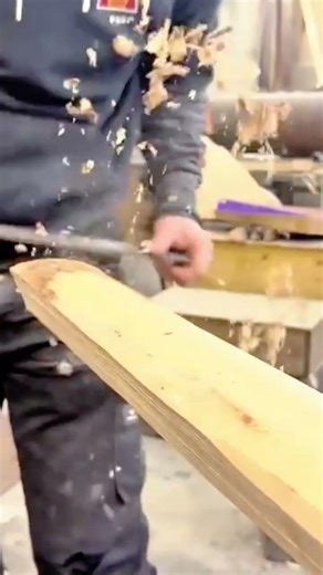 smoothing the edges of a wooden board using a hand file tool in a professional carpentry workshop