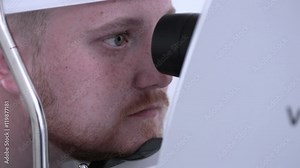 Young male patient on a eye examination. Medical attendance at the optometrist in a bright modern clinic. HD. Stock Video