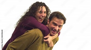 A woman jumps up onto a man's back for a piggy back ride Stock Video