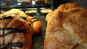 Panning 4K video of fresh pastries in a bakery including chocolate and butter croissants.