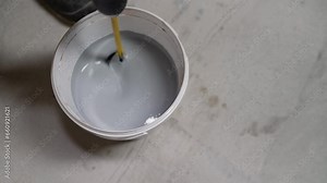 The paint is mixed in a bucket. Water based paint. Mixing water-based paint in a bucket using a construction mixer with a whisk. Mixing paint with a drill.