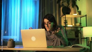 Irritated arguing young woman looking at laptop screen yelling indoors Angry nervous female expressing negative emotion by online conference meeting and close laptop at home at late night