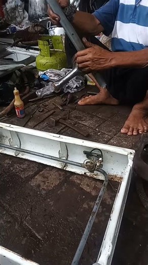 working barefoot on what appears to be metal or plumbing-related work.