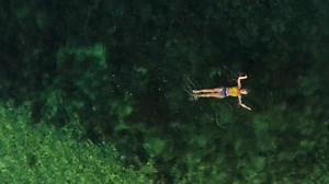 Aerial View Girl Swims in the Ocean