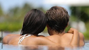 Couple romantic relaxing together in infinity swimming pool in luxury resort spa retreat beach destination.hotel travel vacation. Unrecognizable people relaxed on honeymoon summer holidays.