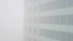 Aerial rising shot of office building in fog