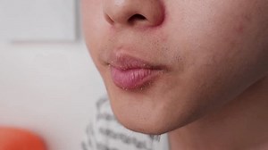 Mouth of asian guy eating chicken burger in slow motion close up