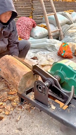Man operates a small mechanical log splitter to quickly divide a thick round piece of wood