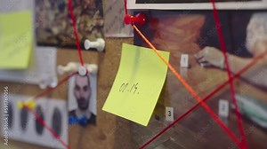 Handheld shot of evidence board with photos, string, pins, and connected evidence
