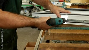 Production and manufacturing of pvc windows, the male worker assembles a pvc profile window, fastens the hinged parts, pvc window, screwdriver