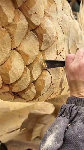 carving artistic scale patterns into a wooden surface using a sharp chisel and precise strokes