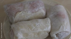 Stuffed cabbage is slowly defrosted on a plate. Close-up of frozen cabbage rolls.