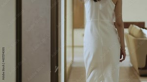 rear view of Asian beauty in white dress walking in living room