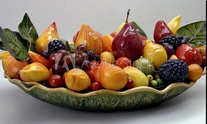A vibrant ceramic fruit centerpiece showcasing various colorful fruits in a decorative bowl.