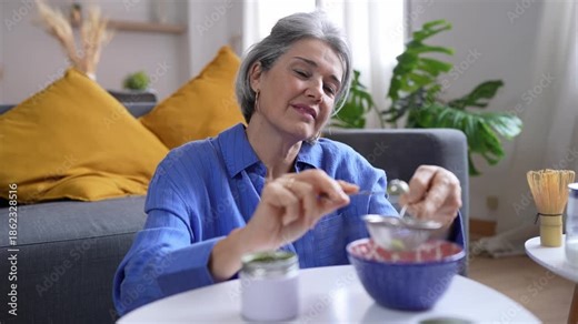 Mature woman preparing traditional matcha green tea at home
