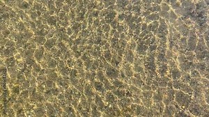 Real shot. A footage taken from above the surface of a shallow, clear stream, revealing pebbles and sand with beautiful reflections. clear shallow.