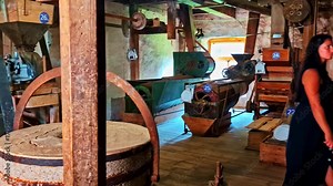 Pan across woman exploring historic woodshop with workbenches and vintage equipment