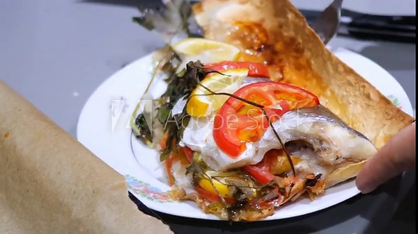 A freshly cooked baked fish with vegetables, beautifully plated and ready to be served on a portioned plate. Serving ready to eat dorado fish, close-up.