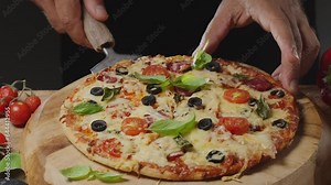 Chef uses a pizza paddle to lift a slice of pizza and in the process stretches the cheese. Traditional Italian food on a dark background.