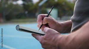 Coach Marks Notes On Notebook In Basketball Court