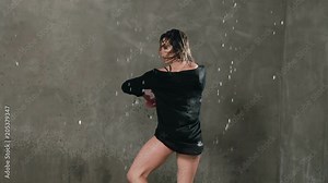 Wet dancer dancing under the drops of water in the studio before studio light, . Rain, wet girl dancer in black clothes makes circles around herself Stock Video