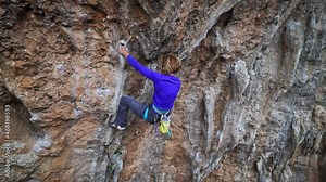 slow motion woman Rock climber on overhanging cliff. female climber trying hard to grip tufa handholds on challenging route.