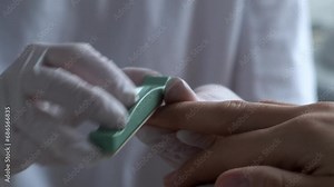 Close-up of a manicurist polishing nails on a woman's fingers on a special hand rest. Manicure process. Self care concept.