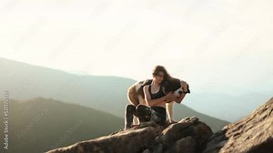 Attractive young woman with a dog saint bernard sitting on the peak and looking at a beautiful mountains view. Animals and human friendship.