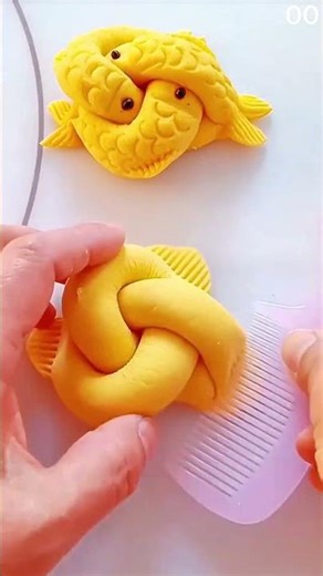 Hands sculpt yellow dough into intertwined fish design