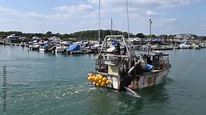 Working Fishing Boat full with Lobster Pots, flag and marker buoys returning from sea to Littlehampton in slow motion.