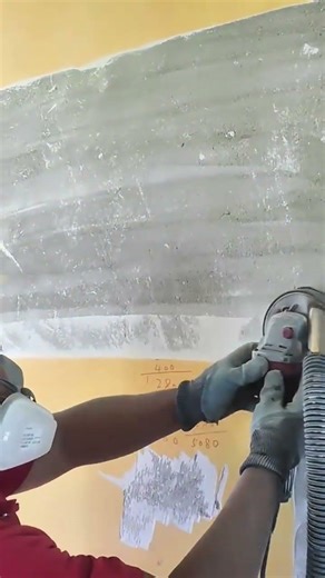 Construction Worker Sanding A Concrete Wall With Power Tool