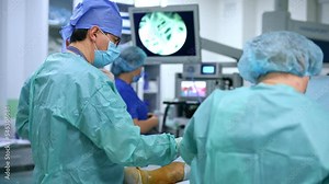 Male doctor performing surgery on patient's foot. Nurse passing the instruments to the chief surgeon. Blurred backdrop.