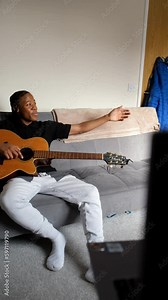 Teenage friends recording music video while sitting on sofa at home