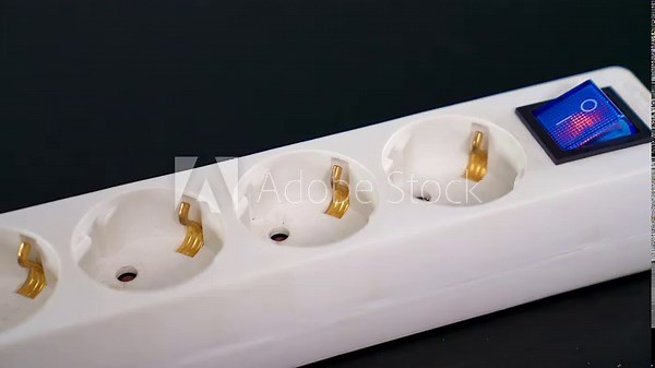 Electrical extension cord with electrical plug. Extension cord on a gray background. The black and white plug are plugged into the socket in the extension cord.