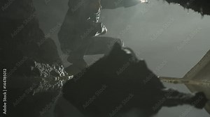 Geologist exploring underground cave, looking at rock formation & water pool