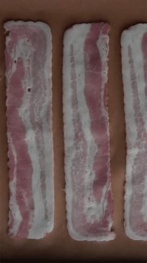 clip-3995552249-raw-bacon-strips-on-parchment-paper-baking