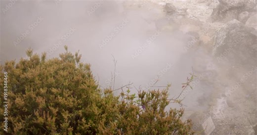 A large bubbling volcanic hot spring pond splashing water and steam at Furnas, Azores.