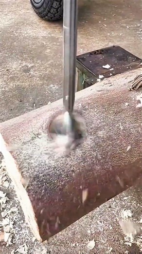Large drill bit boring hole into thick log