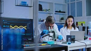 Lab researchers examining biological material under microscope, drug development