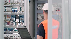 Electrical engineer working check the electric current voltage and overload at front of load center cabinet or consumer unit for maintenance in main power distribution system room. | Premium Stock Video Footage