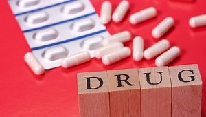 clip-1064899669-capsules-text-drug-on-red-background