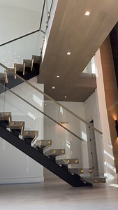 Modern architecture at its finest. This floating staircase defines the space — precision-cut steel stringer, glass railings, and warm oak treads with gold hardware accents. Every detail engineered for beauty, balance, and light. Glass railing by @vitralum.glass.solutions Custom Home Builder @valdaracustomhomes | Custom Stairs