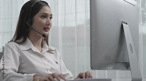 Asian customer support operator wearing headset and microphone working at her desk with laptop. Enthusiastic female employee provide customer service, supportive call center agent helping customers.