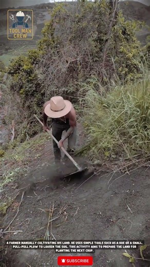 The farmer uses traditional tools (hoe or similar) to prepare farmland in hilly or mountainous areas