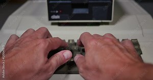 Typing on an old-style 1980s personal computer. Shallow depth of field.