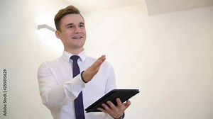 Happy young manager with the tablet. Attractive handsome manager talking and smiling while holding the tablet pc. Happy manager concept