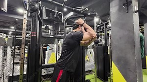 Young fit muscular man close up doing triceps pull down rope extension exercise in modern fitness center