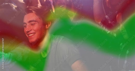 Man wearing grey tee responding to music beat by clapping and nodding amid red green lights