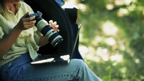 clip-4041579021-photographer-working-laptop-camera-young-holding-while